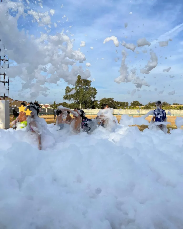 Niños jugando en una fiesta de la espuma al aire libre en verano