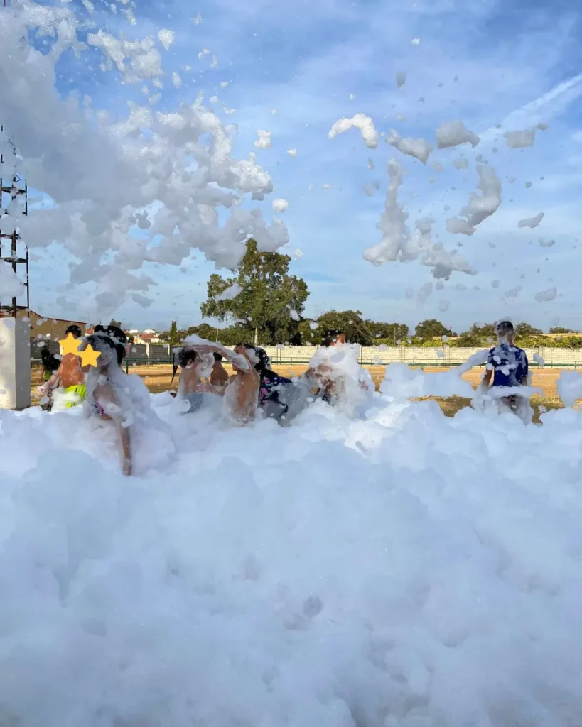 Niños jugando en una fiesta de la espuma al aire libre en verano